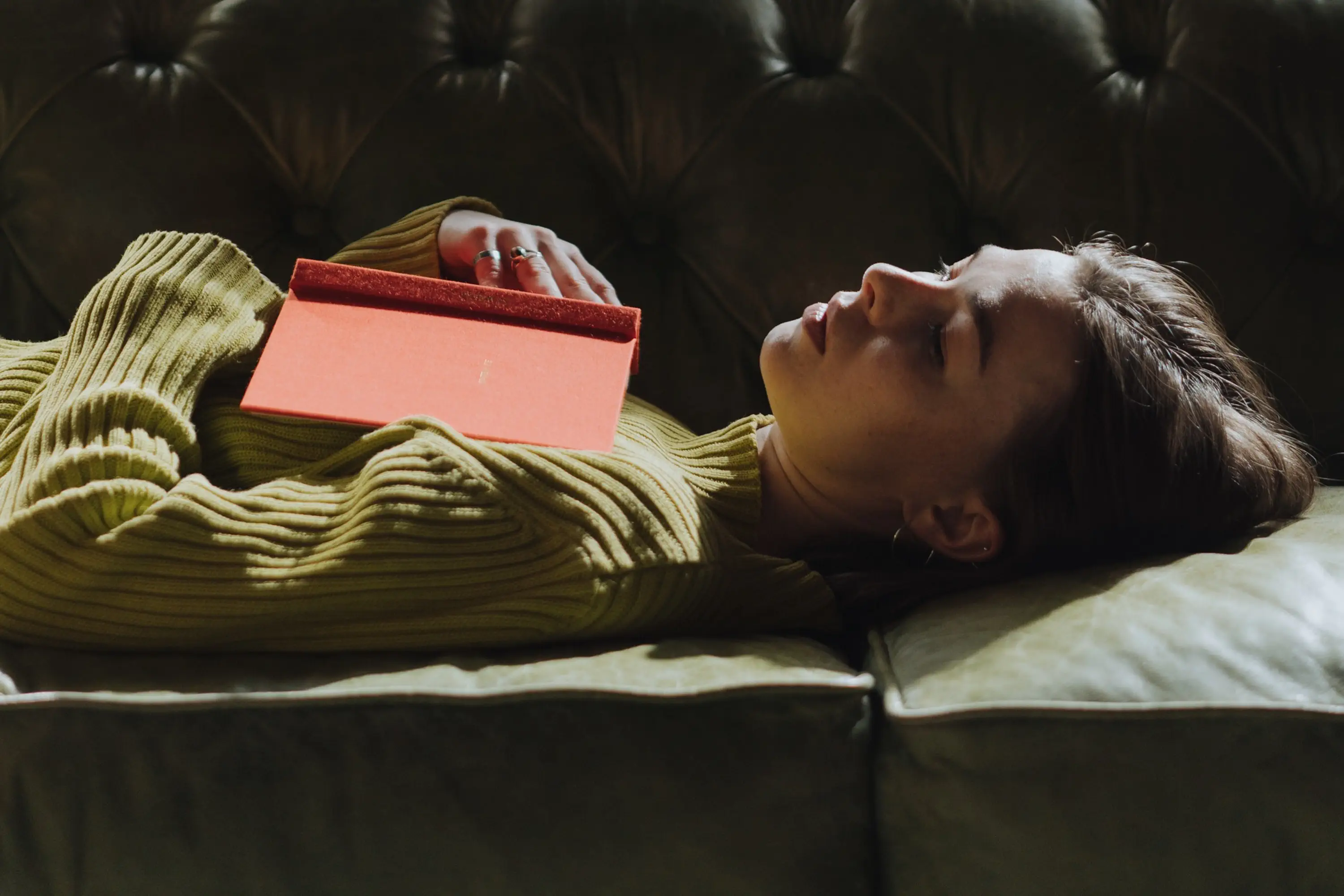 person lying on back with eyes closed and an open book on their chest